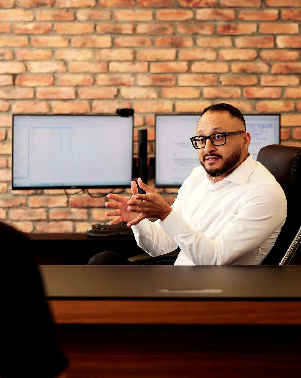 attorney sitting in office chair with 2 monitors behind him