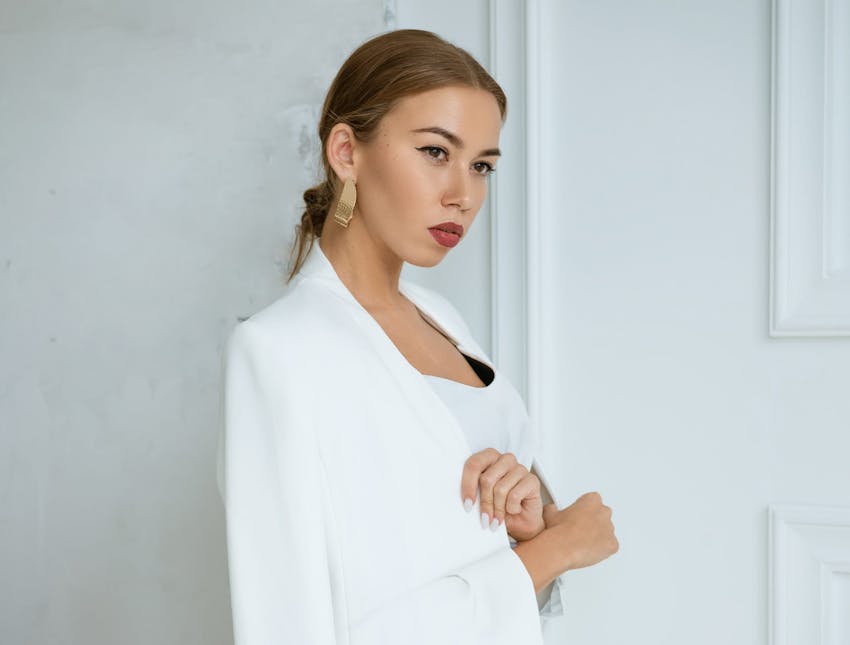woman in white jacket leaning against the wall