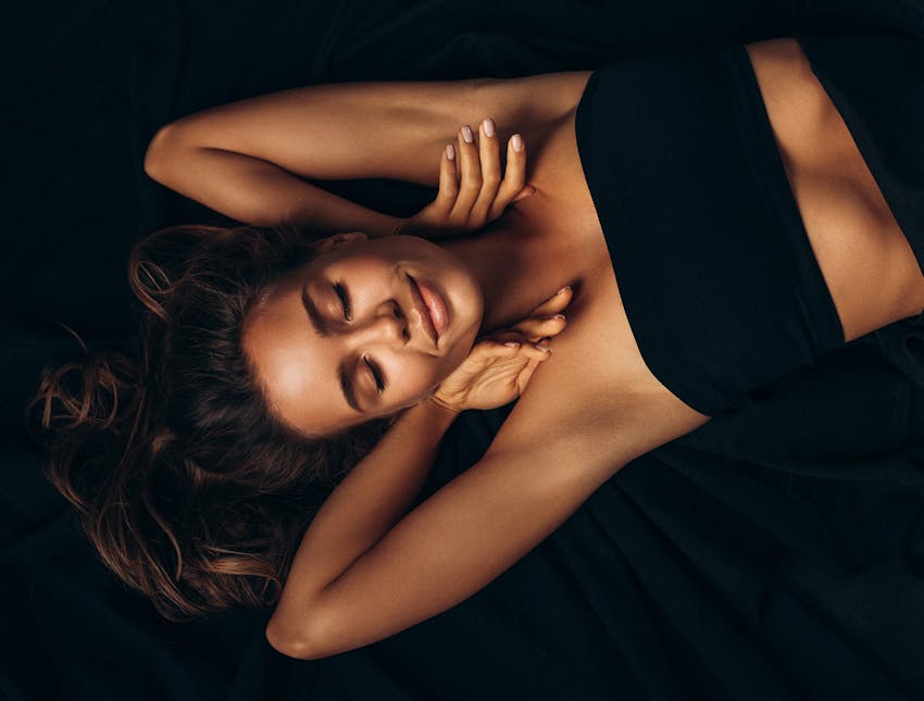 woman laying on bed with both arms upwards
