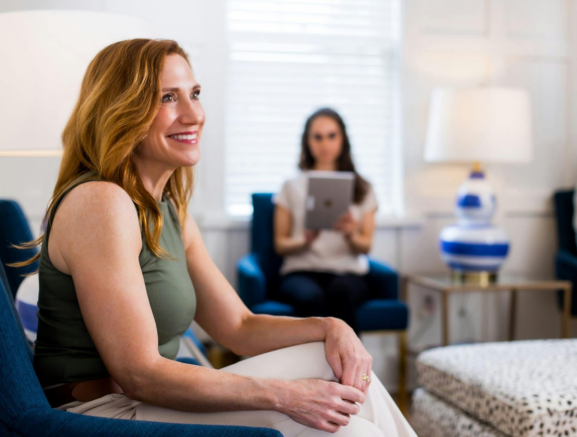 clients sitting in waiting room smiling while one holds ipad