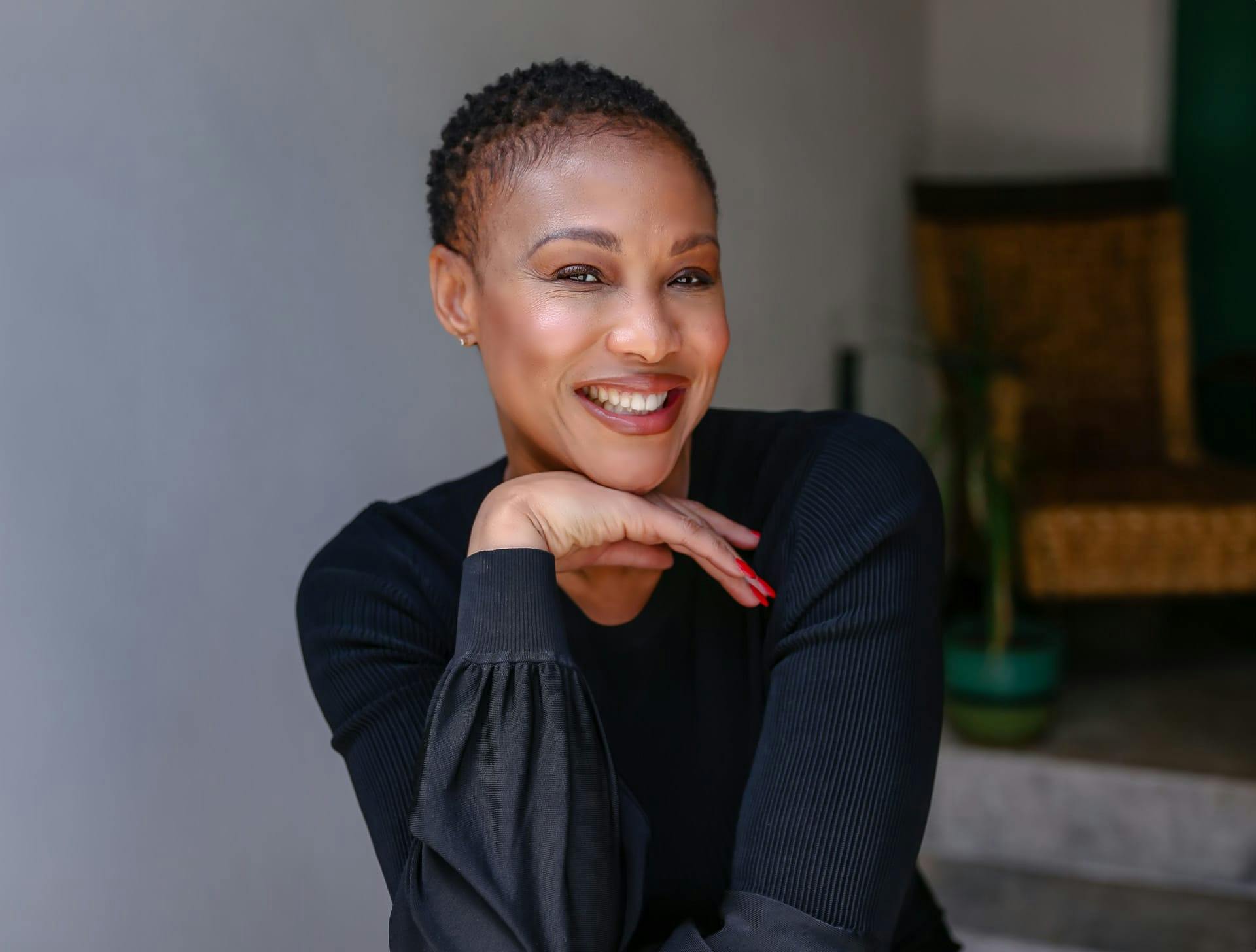 woman smiling and resting her chin on her hand while she sits down