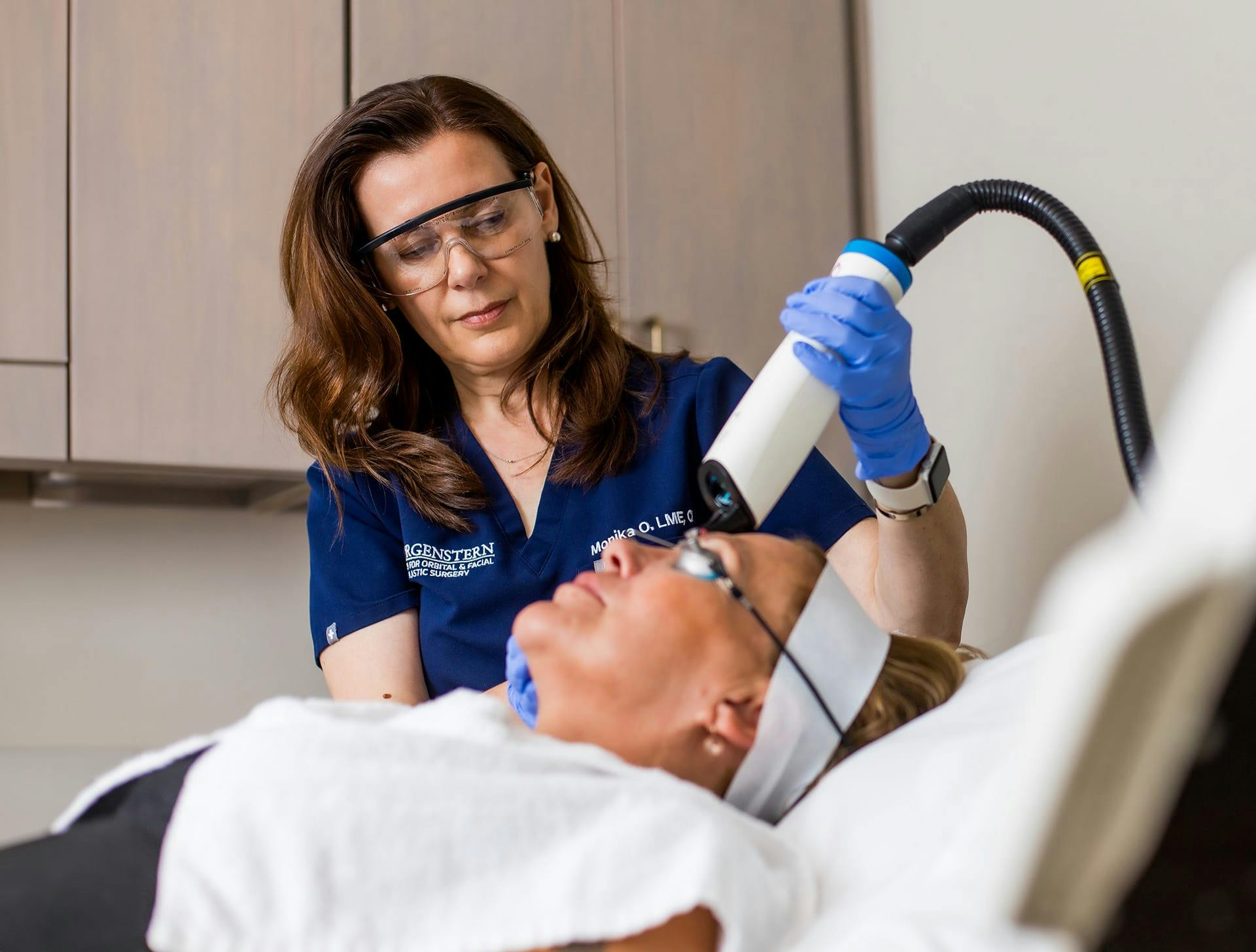 nurse doing laser treatment on client as they lay down