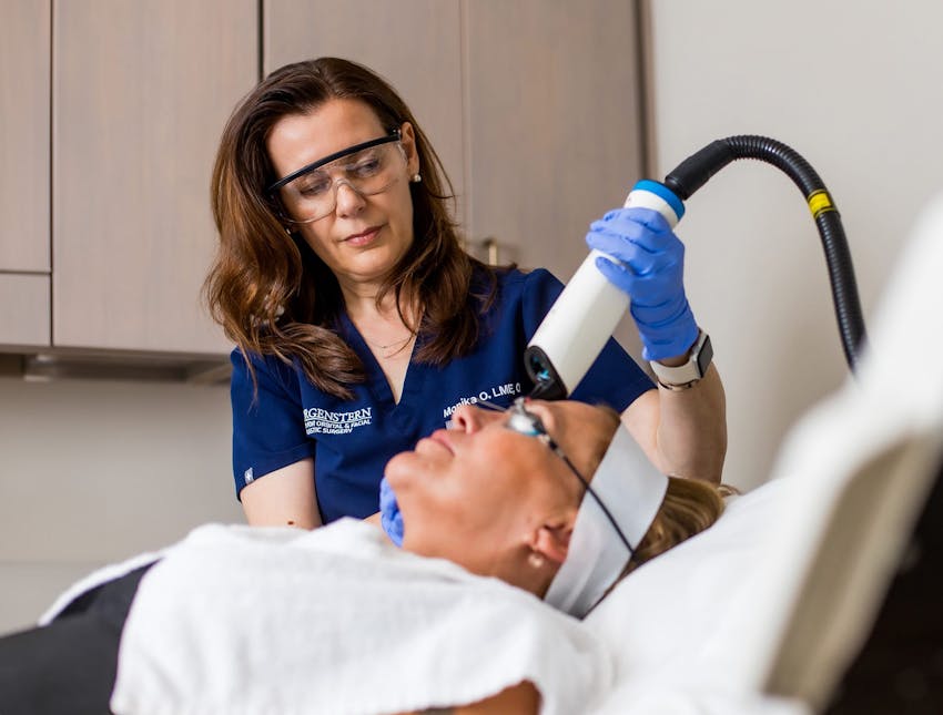 nurse doing laser treatment on client as they lay down