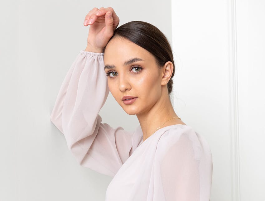 woman in white see-through shirt with slick bun