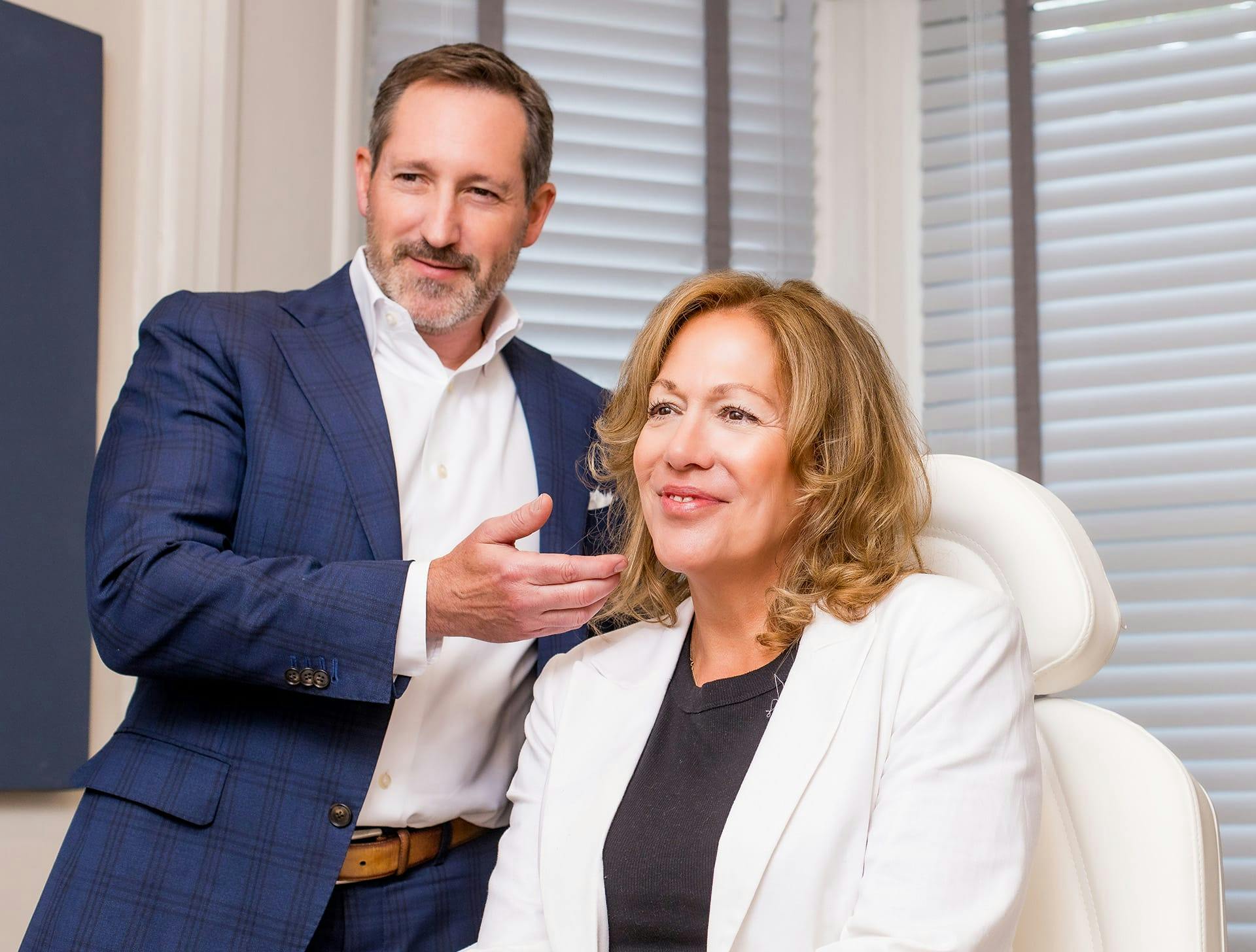 Dr. Morgenstern with client sitting in chair both looking in mirror
