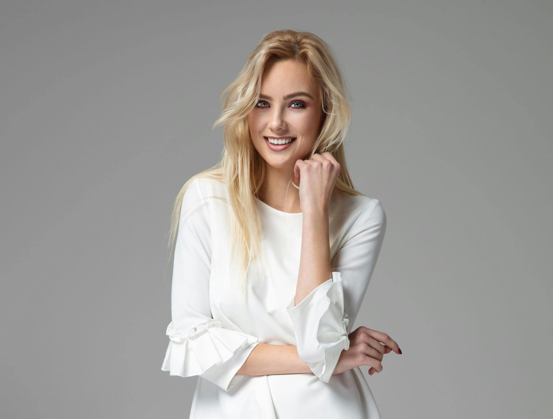 woman in white long-sleeved dress with his fist to her chin