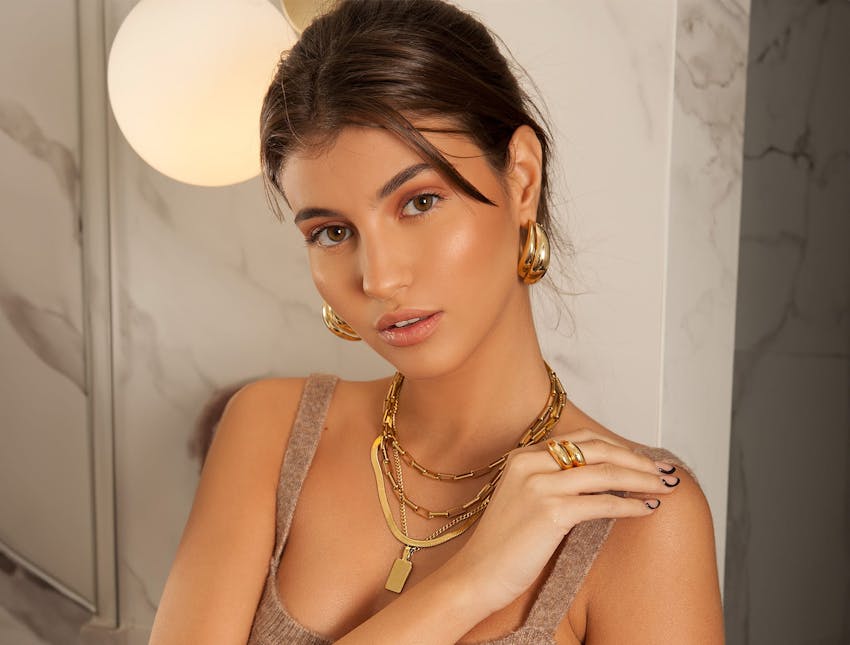 woman in tan top with hair pinned up in gold jewelry