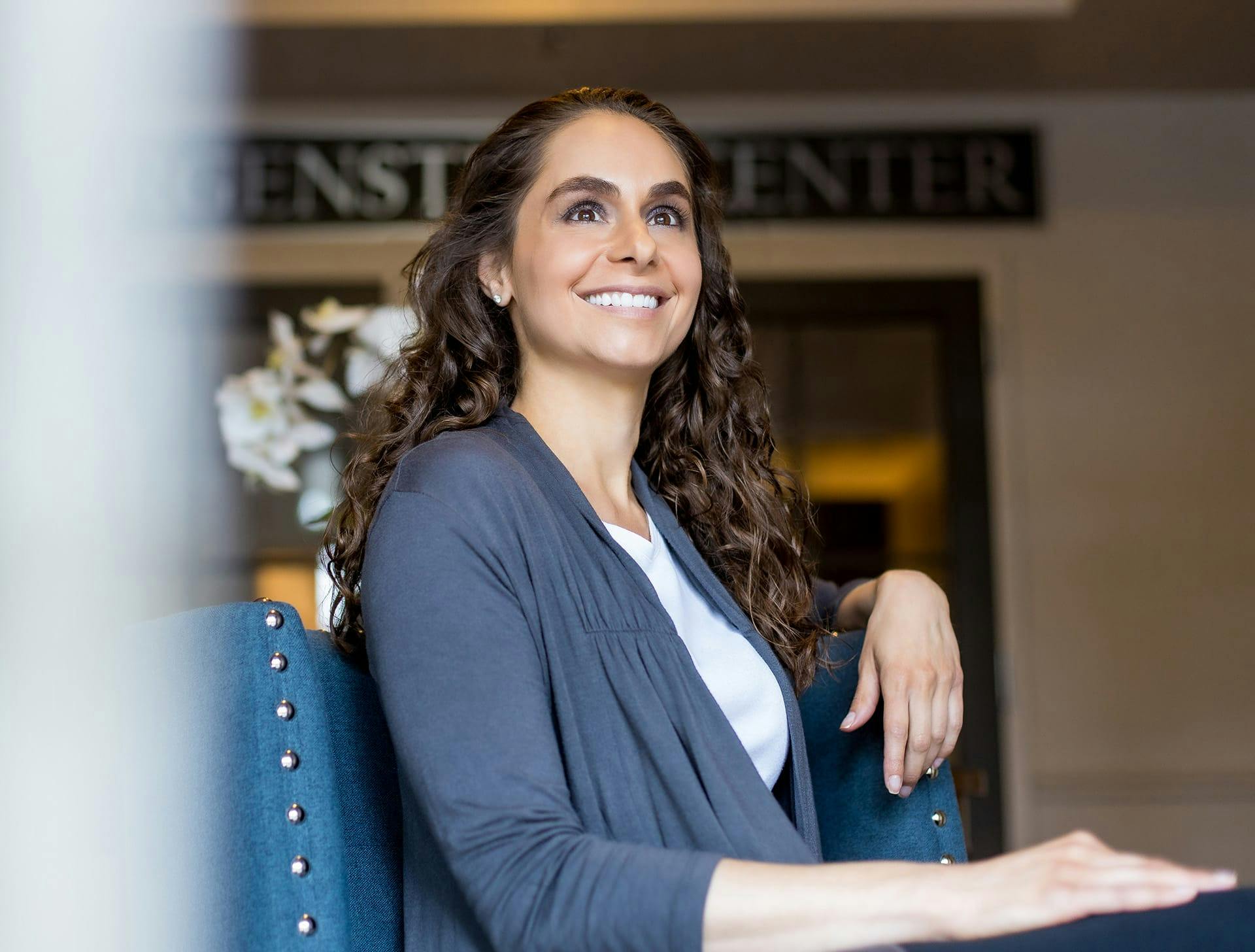 woman with curly brown hair sitting in chair