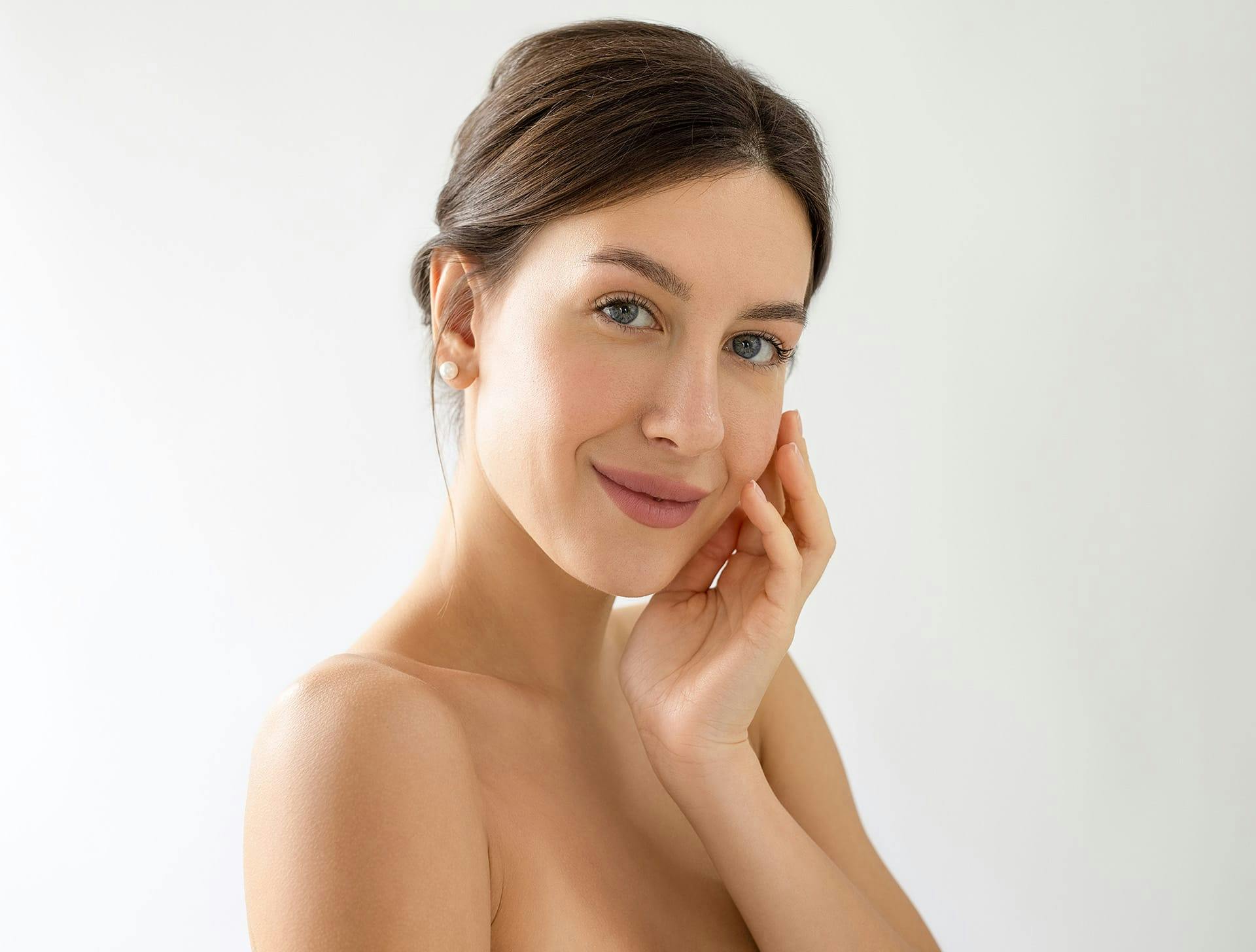 woman with low bun touching her cheek with her hand