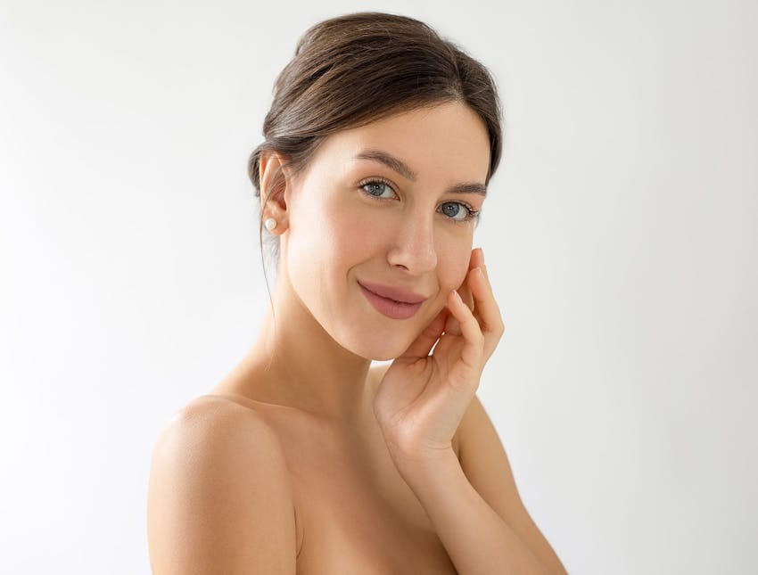 woman with low bun touching her cheek with her hand
