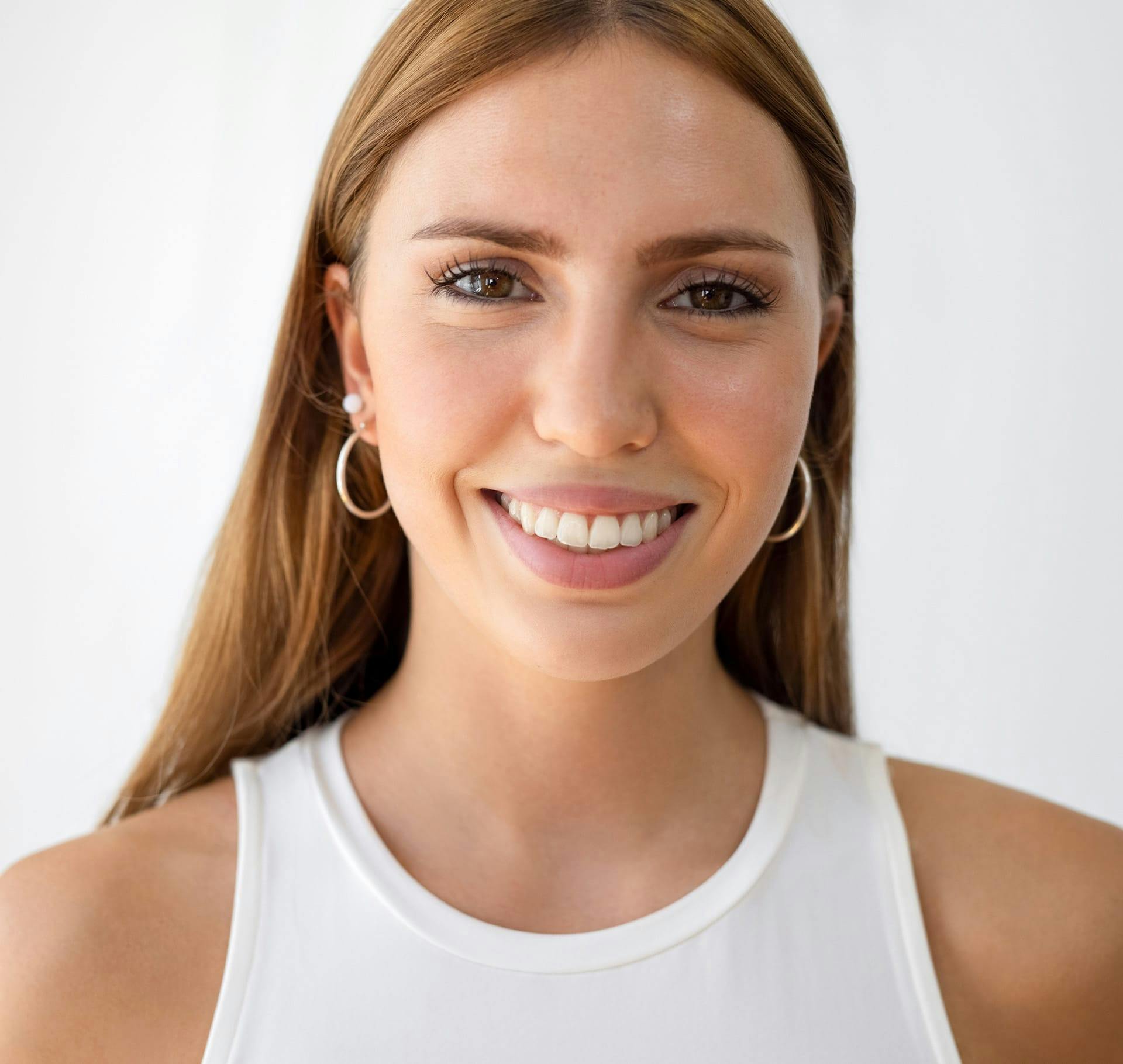 woman with red hair in white tank top smiling