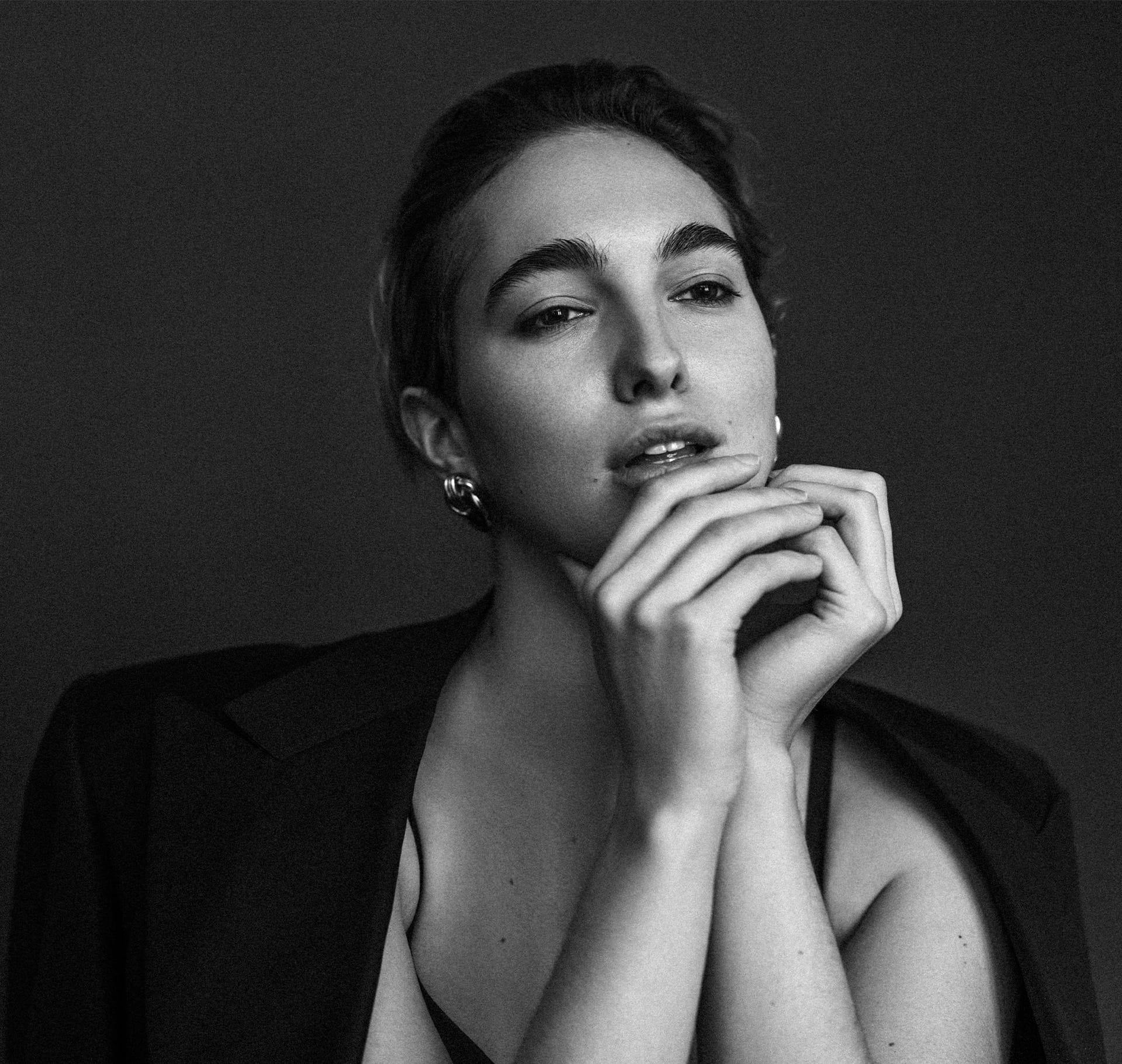 greyscale of woman with suit jacket over her shoulders and hands touching together