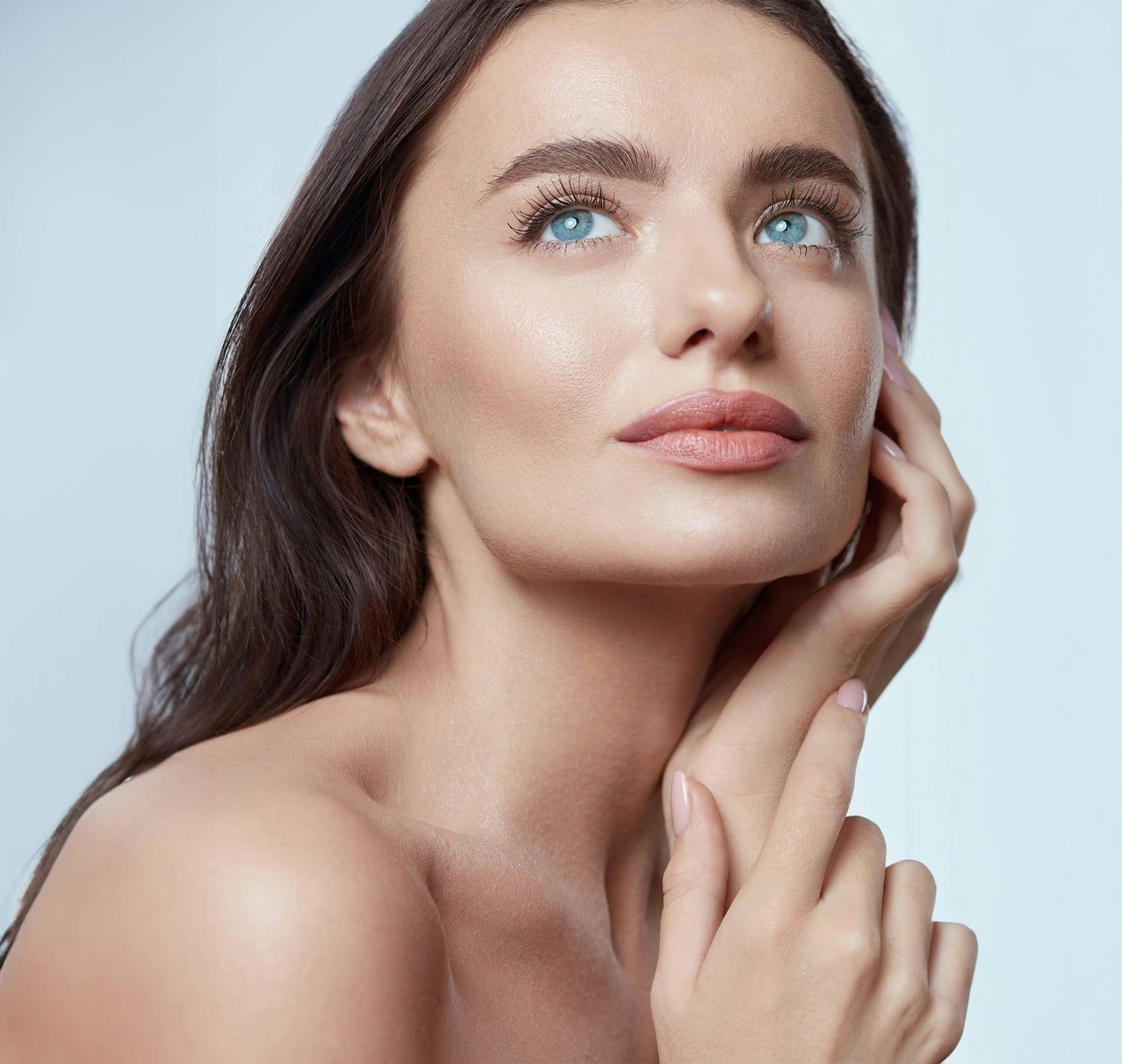 woman with blue eyes looking up with hand on side of face