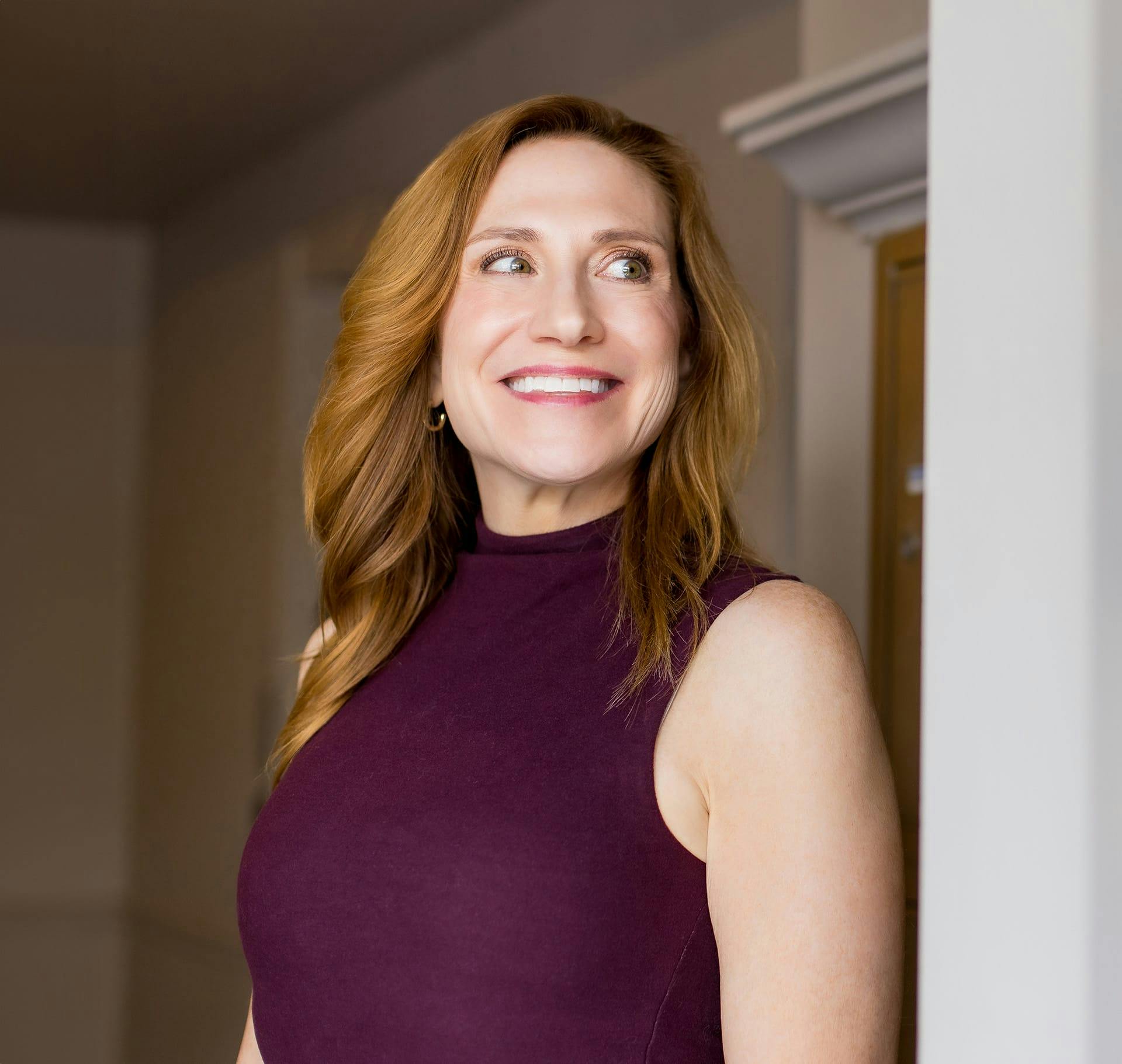 woman with red hair smiling in purple top