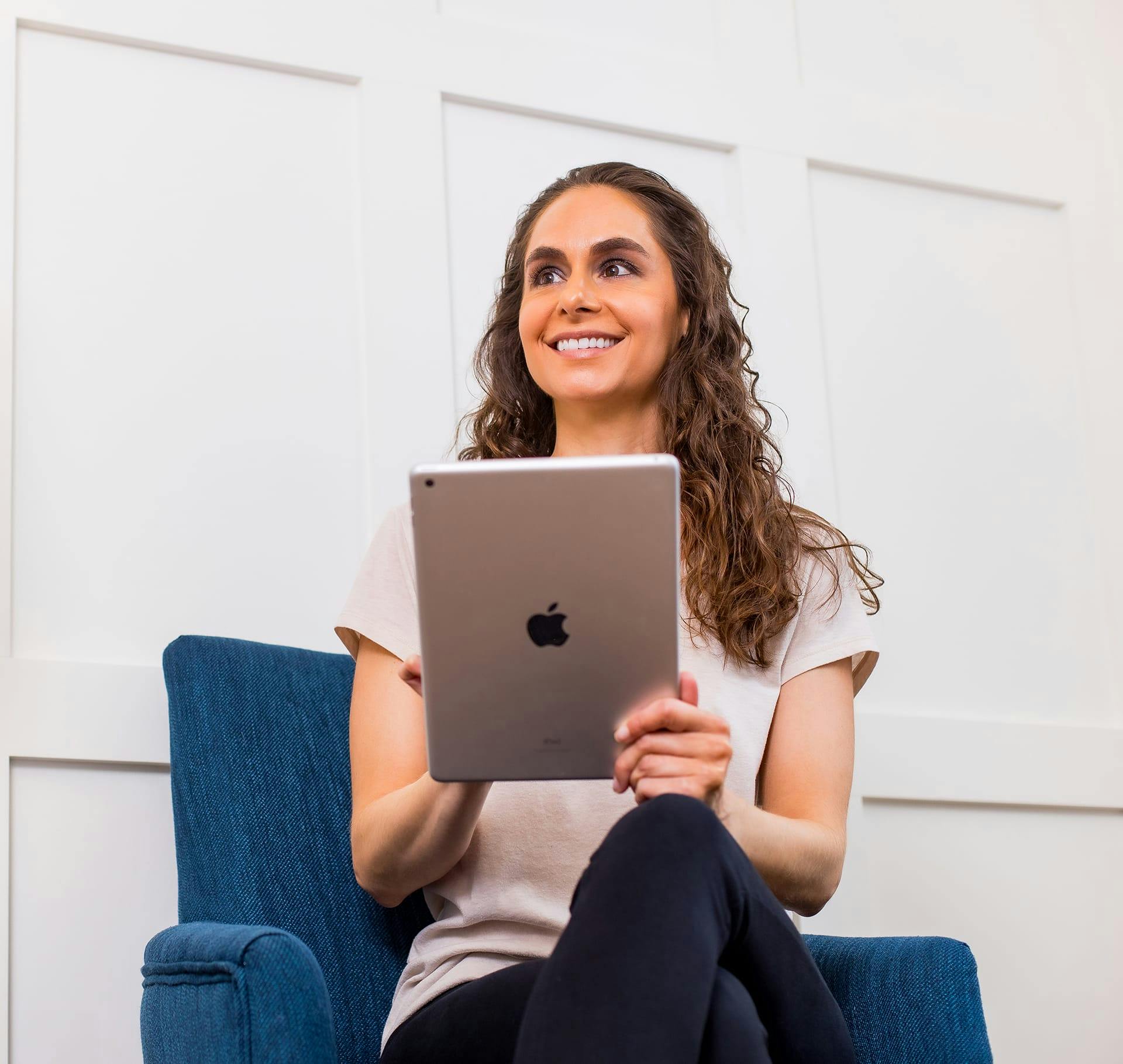 woman smiling while holding an ipad