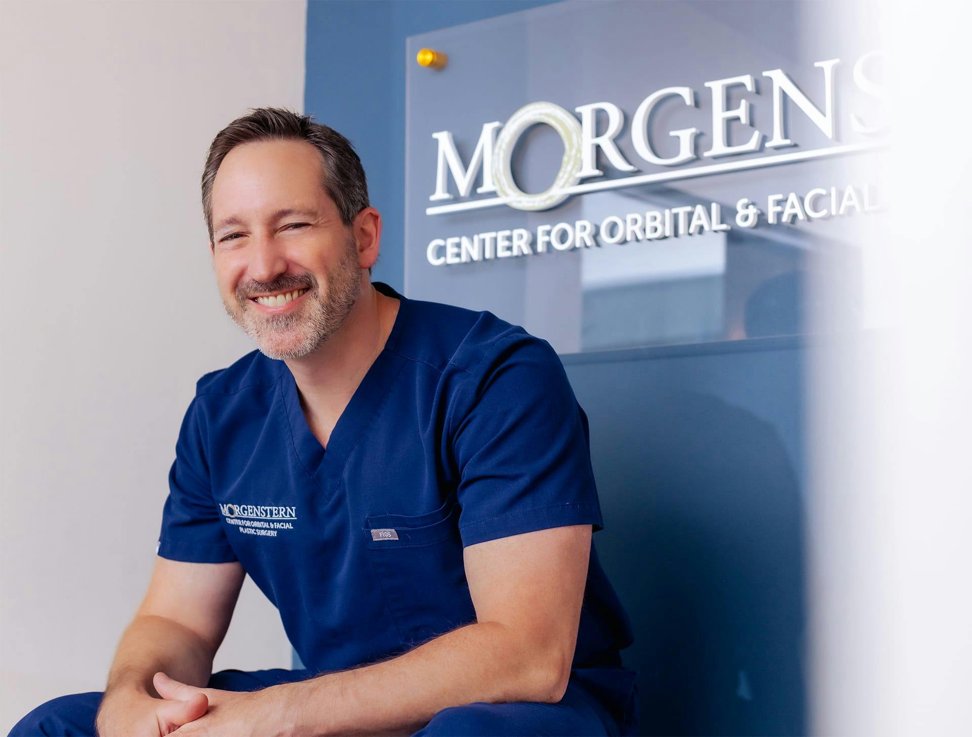 Dr. Morgenstern in attire sitting in front of his logo center