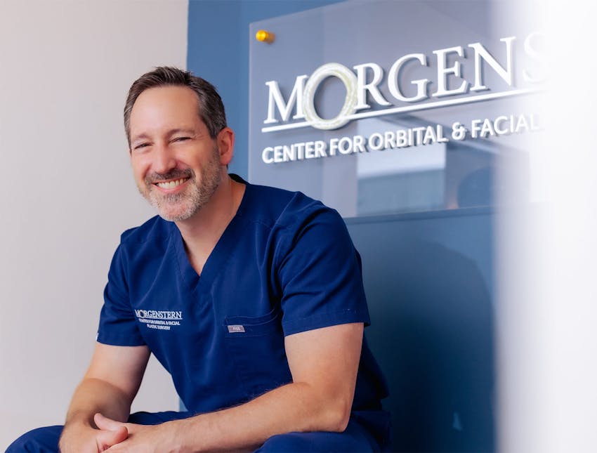 Dr. Morgenstern in attire sitting in front of his logo center
