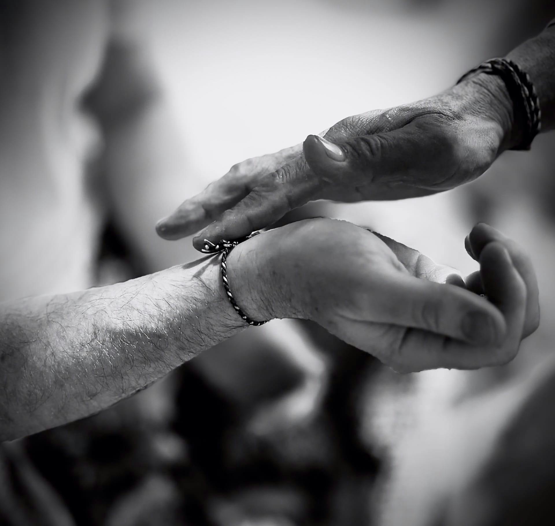 greyscale of a finger touching a wrist of another person