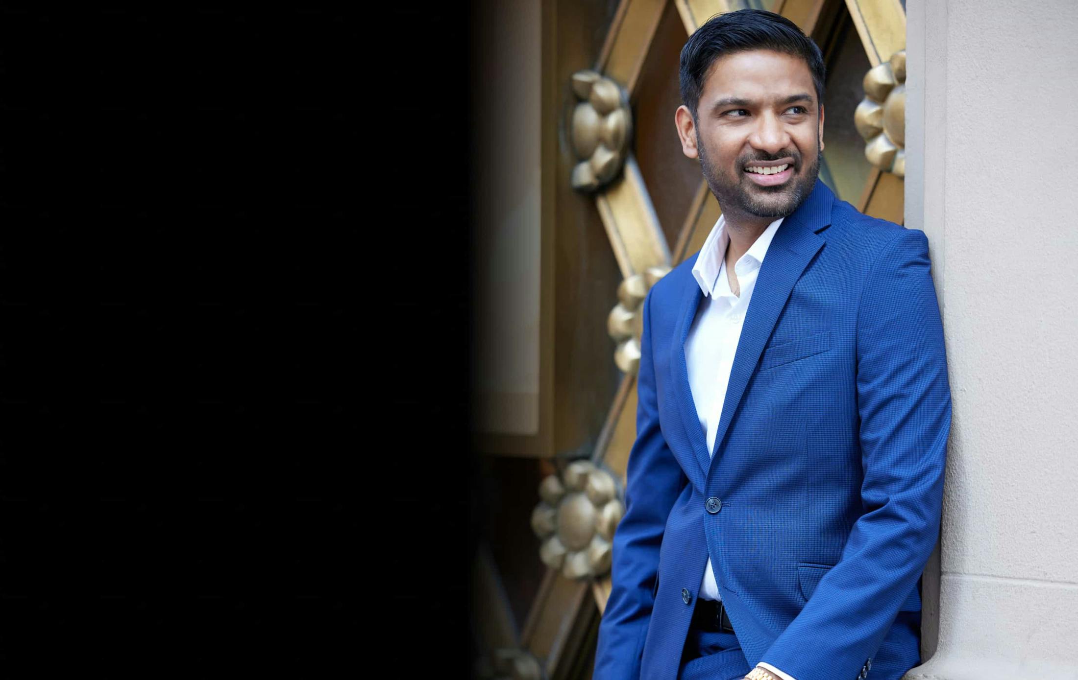 Dr. Singh smiling and leaning against a wall