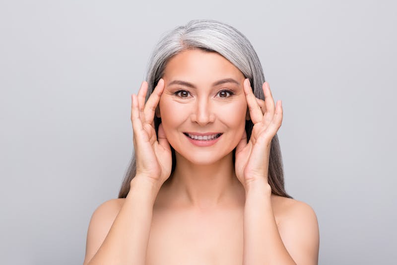 older woman touching her face