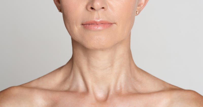 Close-up of a woman’s lower face, neck, and shoulders.