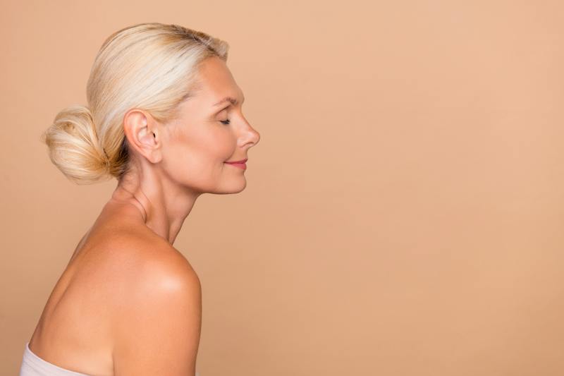 Side profile of a mature blonde woman showing her jawline and neck.