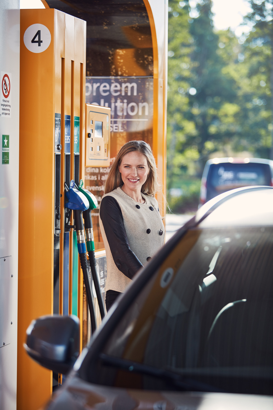En kvinnlig förare tankar sin bil på en Preemstation.