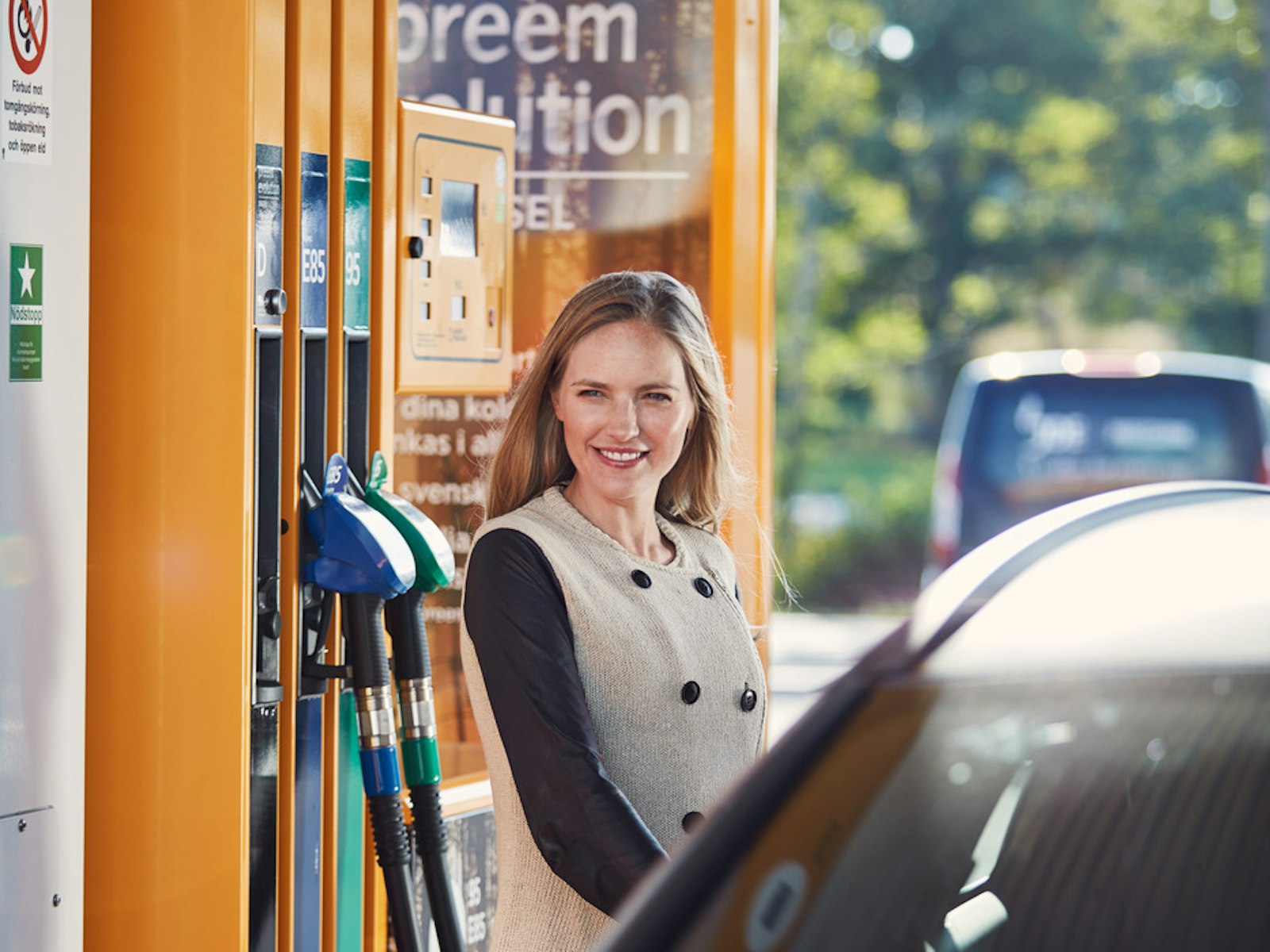 En kvinnlig förare tankar sin bil på en Preemstation.