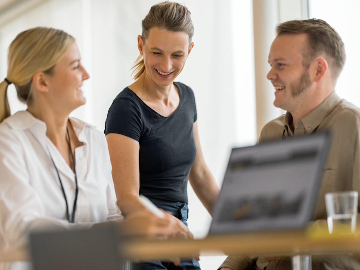 Tre glada personer vid ett bord.