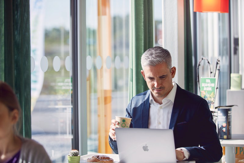 Person dricker kaffe vid sin dator inne på en Preem-station.