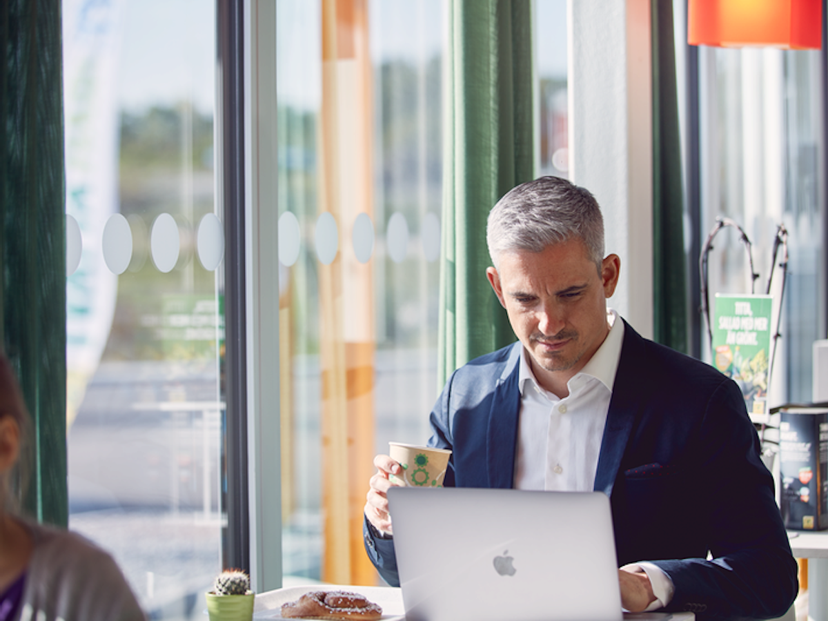 Person dricker kaffe vid sin dator inne på en Preem-station.
