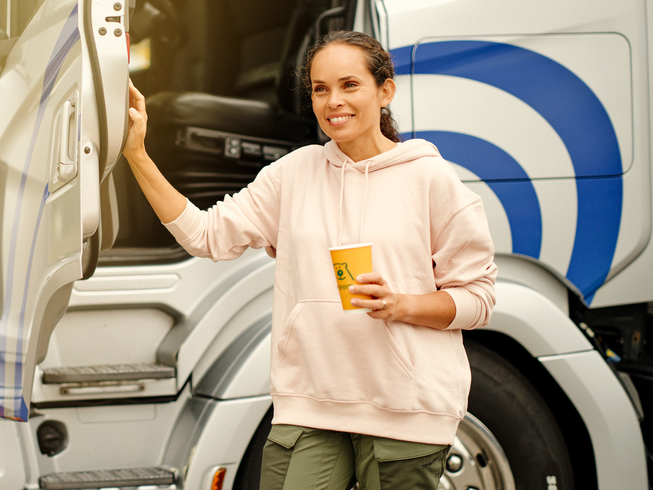 Kvinnlig yrkesforare framfor sin lastbil på en Preemstation.