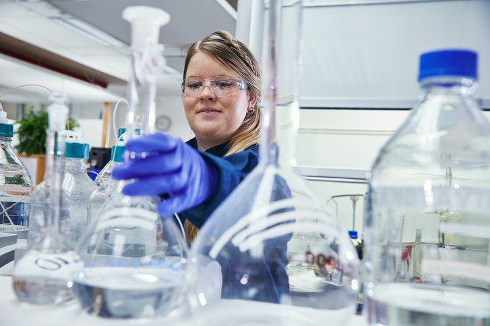 Person med glasflaska på Preems raffinaderi.