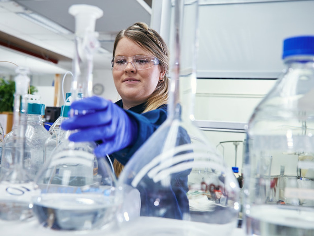 Person med glasflaska på Preems raffinaderi.