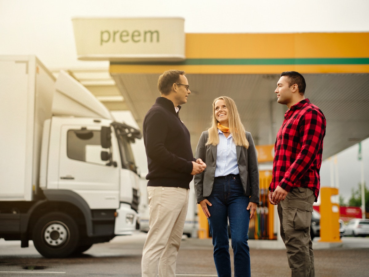 Tre personer står och pratar med varandra utanför en Preem-station