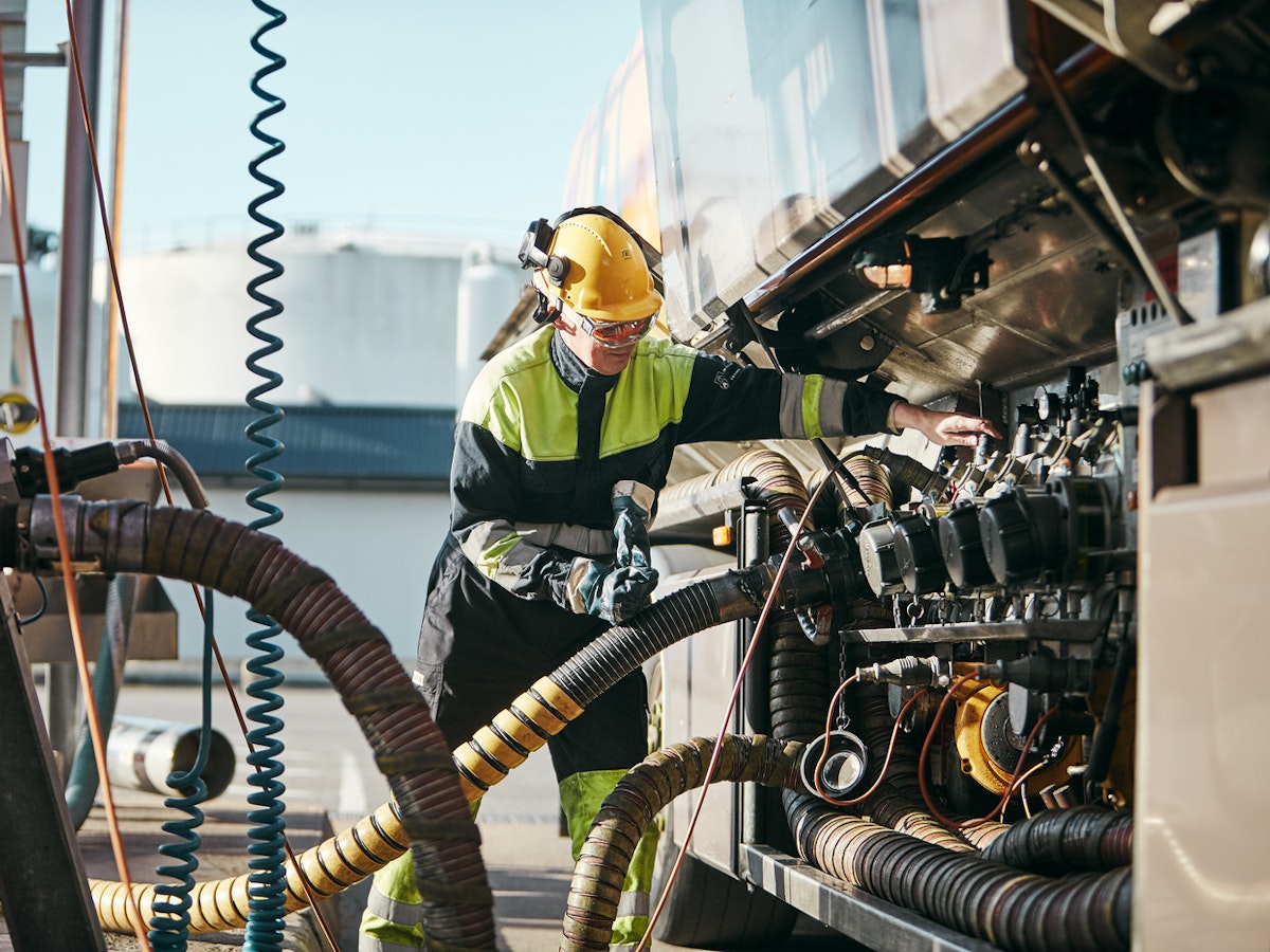 Person fyller på drivmedel på stort fordon