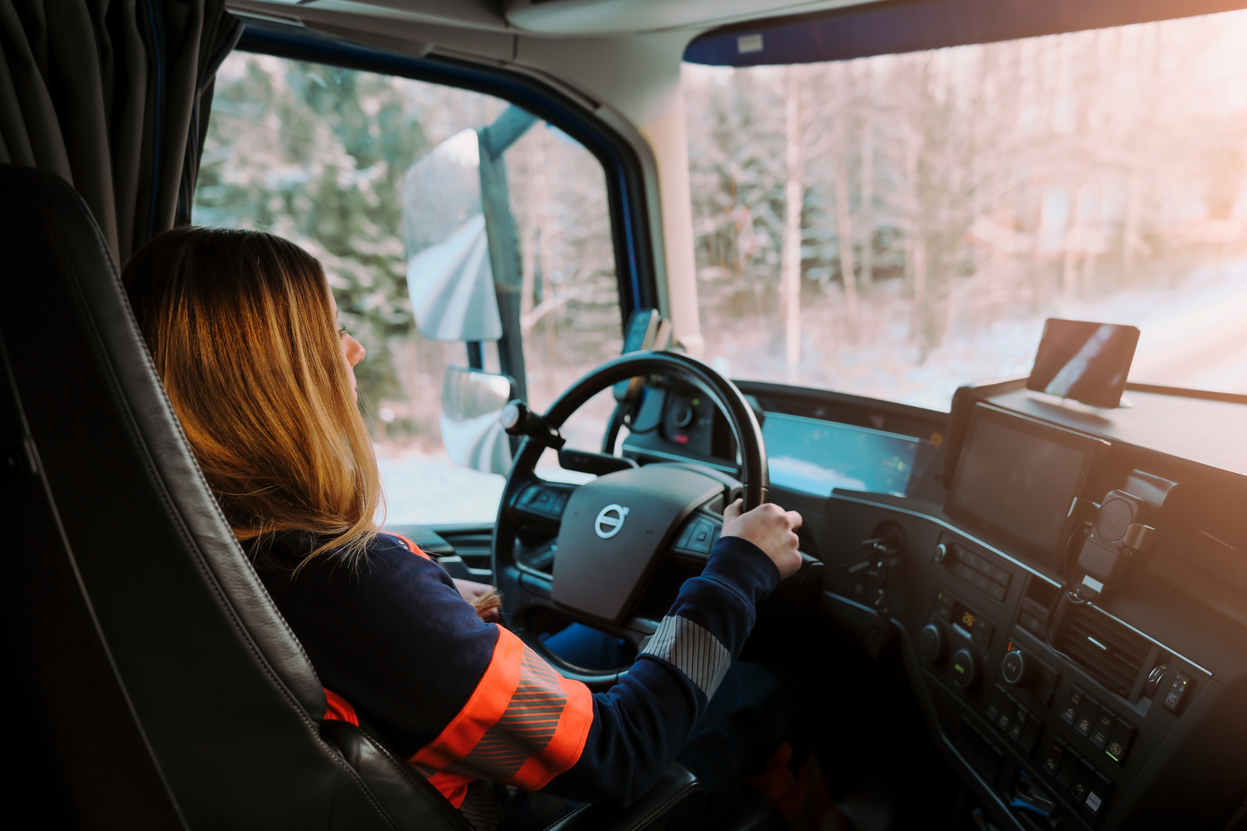 En kvinnlig lastbilsförare i sin förarhytt.