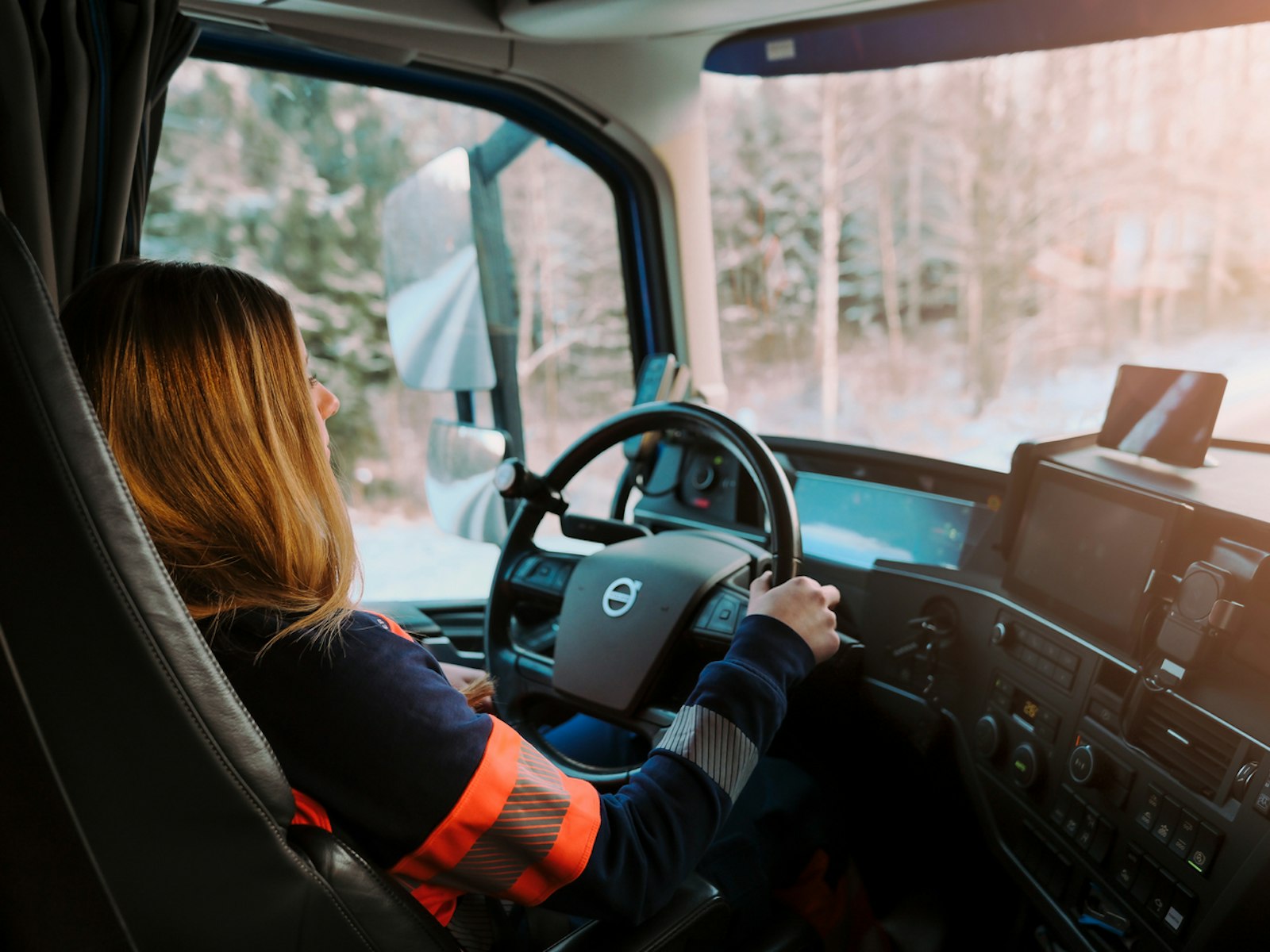 En kvinnlig lastbilsförare i sin förarhytt.