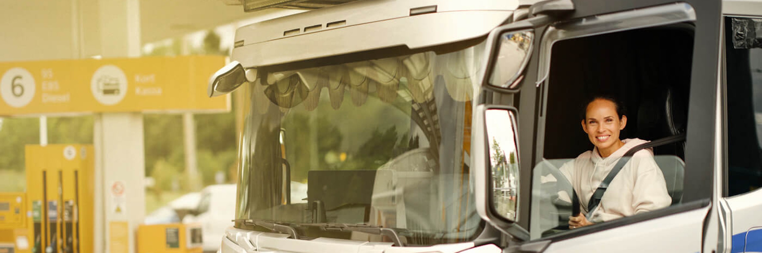 Kvinnlig lastbilschaufför i sin lastbil på Preem-station