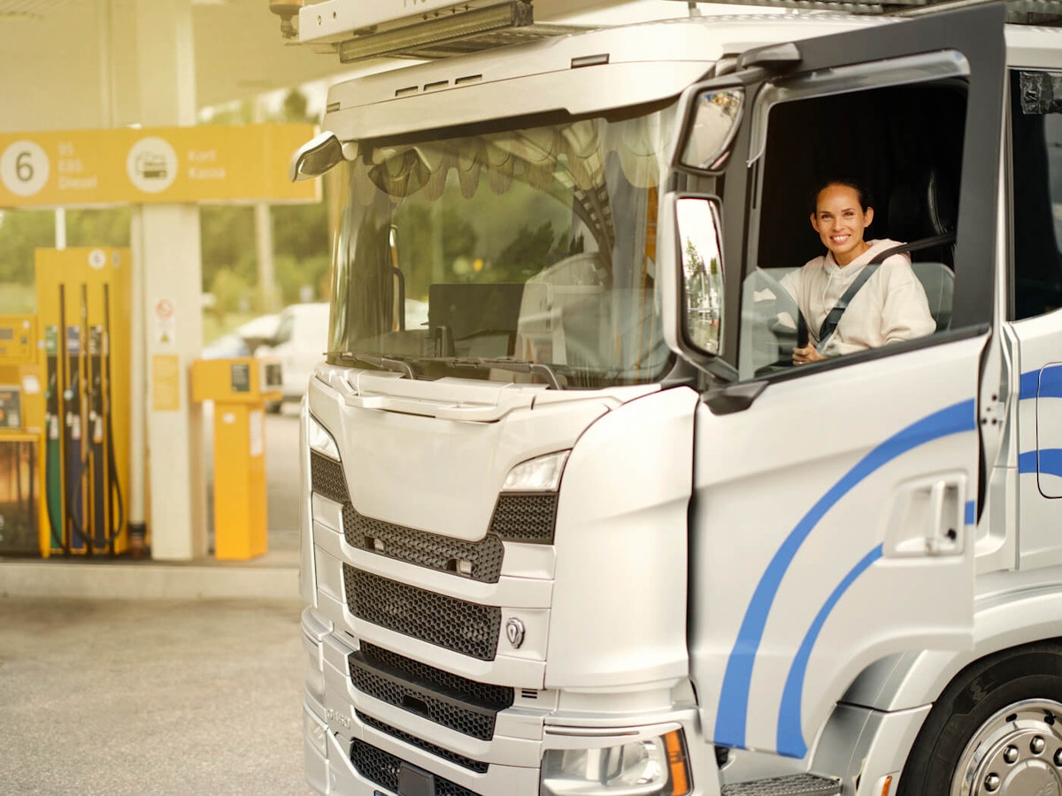 Kvinnlig lastbilschaufför i sin lastbil på Preem-station