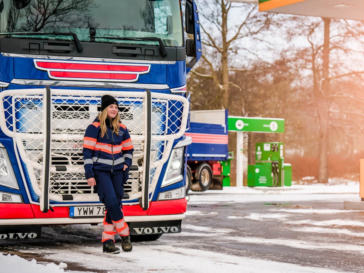 Kvinnlig lastbilschaufför står framför sin lastbil vid en Prestation.
