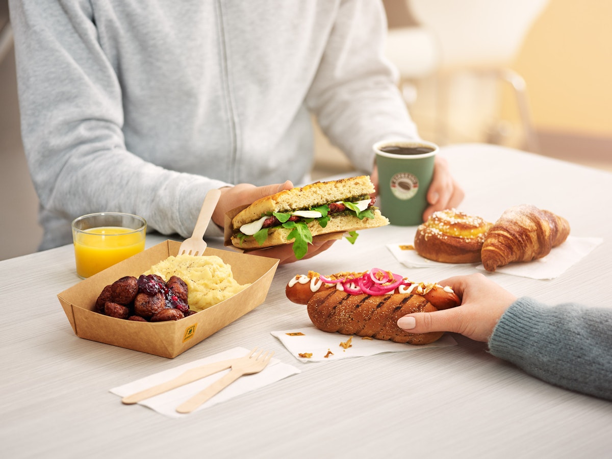 Två personer vi ett bord som håller i en korv och en foccaccia