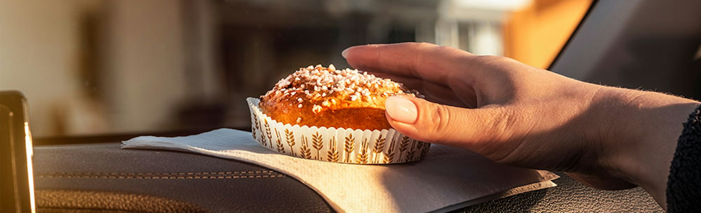 En hand som sträcker sig efter en nybakad bulle i en bil