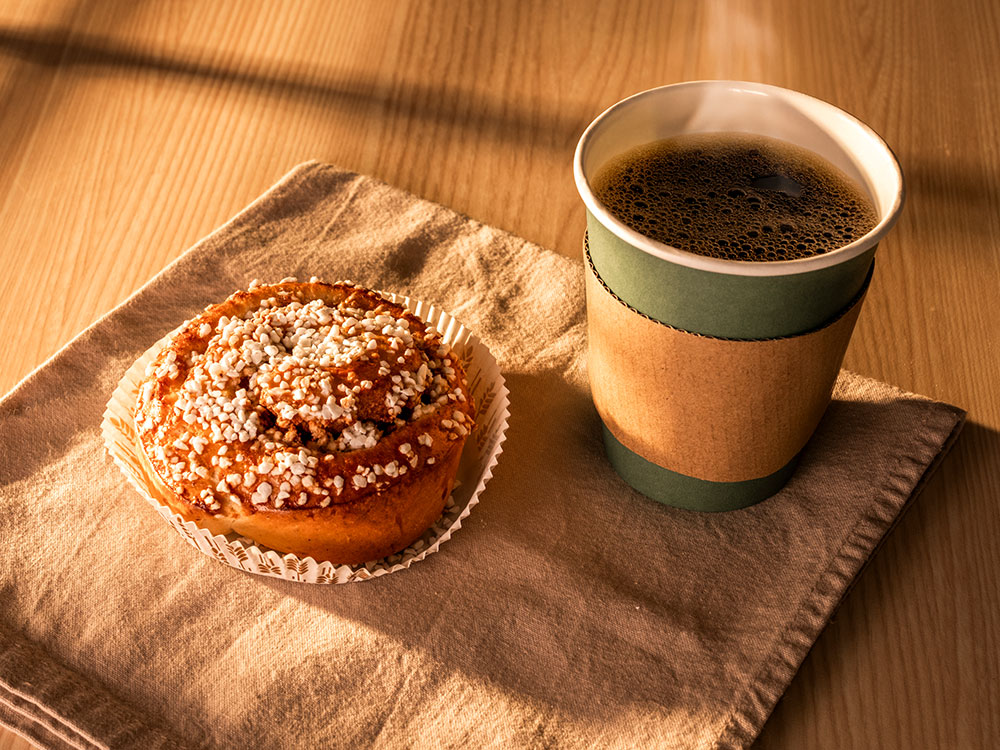 Kanelbulle med en kaffekopp i en takeaway mugg