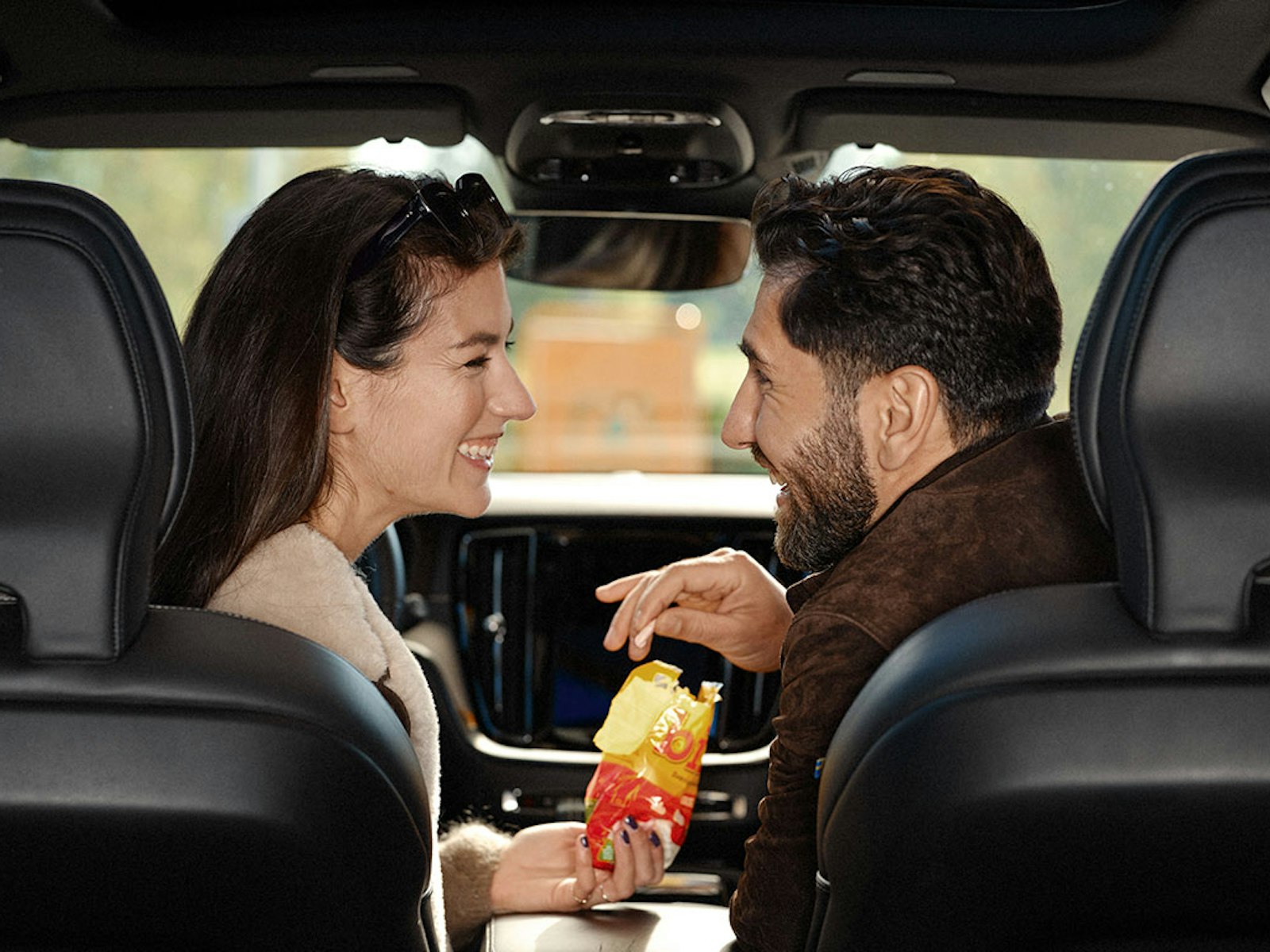 Ett par sitter i en bil och delar på en påse Ahlgrens bilar