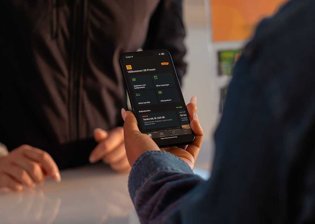 Hand som håller i en telefon som visar Preem-appen