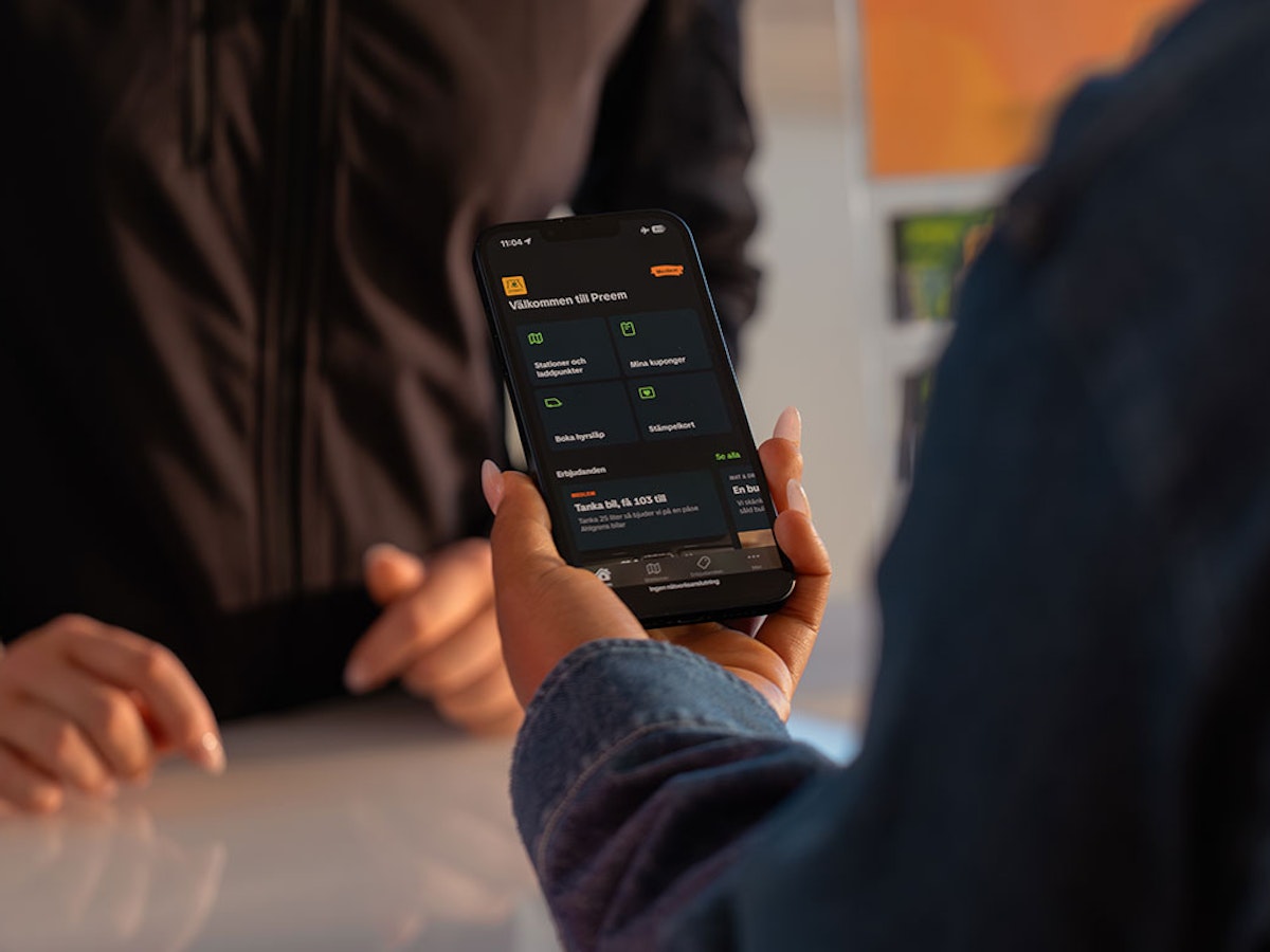 Hand som håller i en telefon som visar Preem-appen