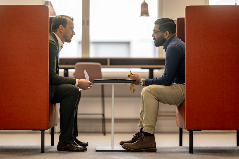 Två män sitter i en varsin fåtölj och pratar med varandra