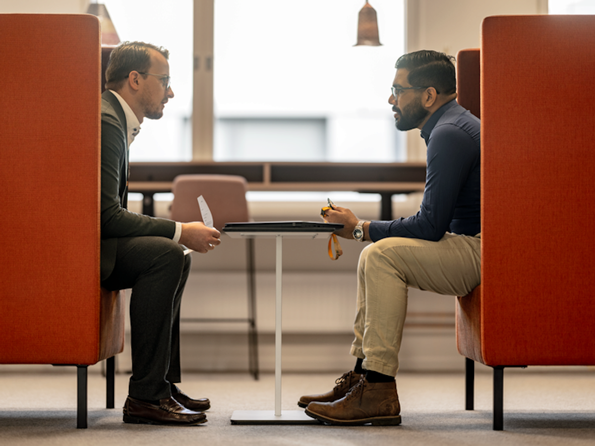 Två män sitter i en varsin fåtölj och pratar med varandra