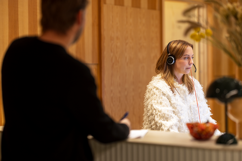 Kvinna sitter i en reception och pratar i telefon